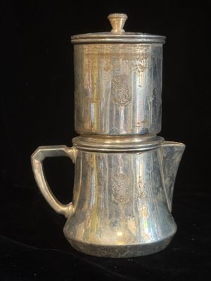une cafetière en argent et une théière en argent sur fond noir