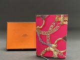 an orange and pink notebook with a gold chain on it