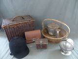 un panier, un chapeau, une théière, une bouilloire et d'autres objets posés sur une table