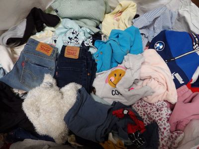 a pile of clothes that is sitting on a bed