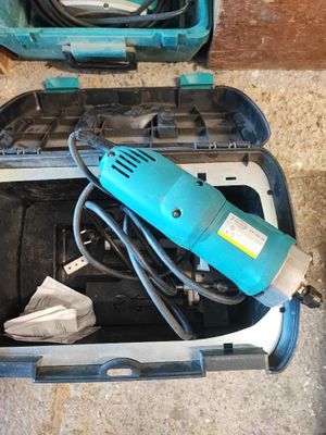 une perceuse électrique bleue dans un coffret posé par terre