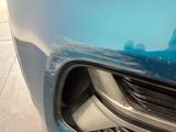 a close up of a car ' s front grill with a reflection of a person in the background