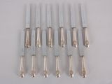 eight silverplated knives with handles and handles on a white surface