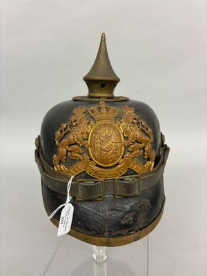 an old helmet with a gold decoration on top of a glass stand