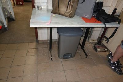 une table sur laquelle se trouve un sac, avec une poubelle devant
