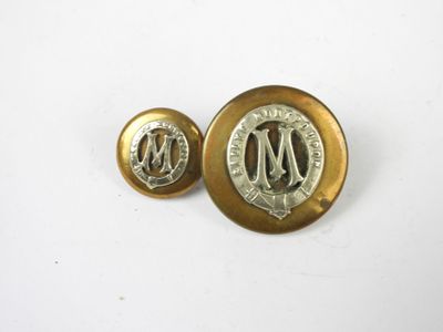 une paire de boutons dorés et argentés sur lesquels figure la lettre « m »