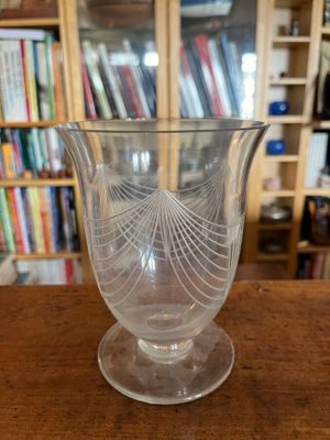 a glass vase sitting on a table in front of a bookshelf