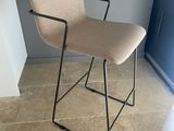une chaise beige aux pieds et accoudoirs noirs, placée devant une porte bleue