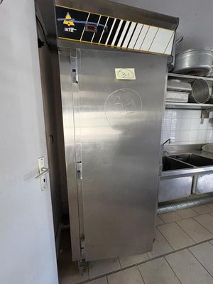 a stainless steel refrigerator in a kitchen with pots and pans on the counter