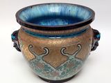 a blue and gold vase sitting on a white surface