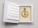 a small gold medal in a white box with a quote on it