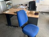 a blue office chair sitting in front of a computer desk