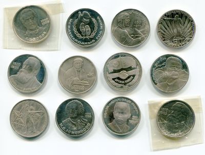 Plusieurs pièces de monnaie différentes sont présentées sur une surface blanche, accompagnées d'un petit bout de papier