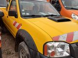 yellow pick up truck parked in a lot with other trucks in the background