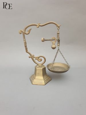 a gold scale with a coin on it on a white surface