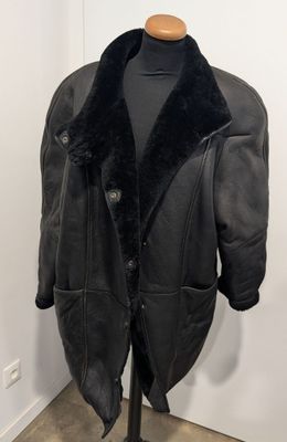 La veste est noire et est dotée d'un col en fourrure.