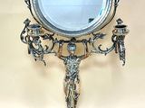 un miroir posé sur un pied, sur lequel se trouve une statue