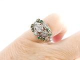 an image of a woman ' s hand holding a diamond and emerald ring