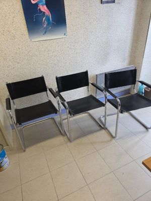 three chairs in a waiting room with a painting on the wall