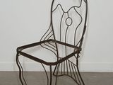 wrought iron chair in the shape of a fish on a concrete floor