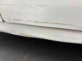 a white car that has some rust on the side of it