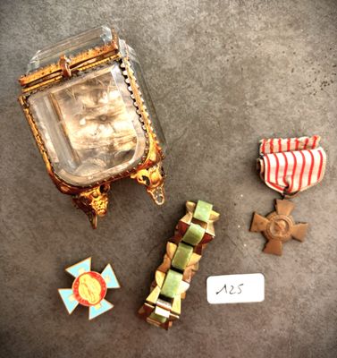 une petite boîte contenant une médaille et d'autres objets, posée par terre