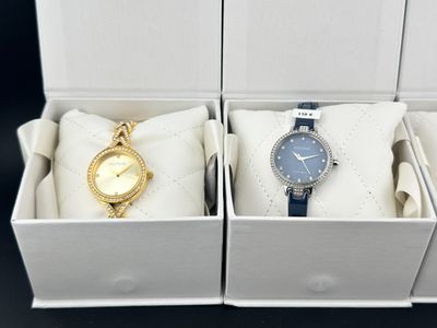 deux montres dans un coffret blanc : une montre dorée et une montre bleue