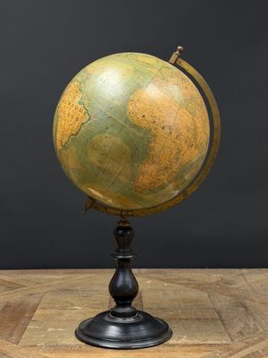 un vieux globe terrestre posé sur une table en bois, sur fond noir