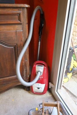 a red vacuum that is sitting on the floor next to a window