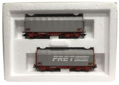 deux wagons de train miniature dans une boîte blanche posée sur une surface blanche
