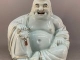 a statue of a laughing buddha sitting on the ground