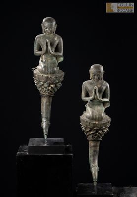 deux statues de Bouddha en bronze, assises sur un socle noir