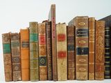 many old books lined up on a shelf together