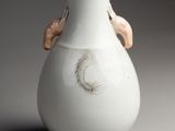 a white vase with a gold handle on a gray background