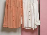 two shirts hanging on a rack in front of a pink and white wall
