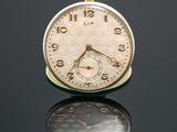 a close up of a pocket watch on a reflective surface