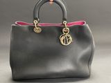 a person holding a black purse with a pink handle