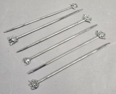 six cuillères en argent sont alignées sur une surface blanche