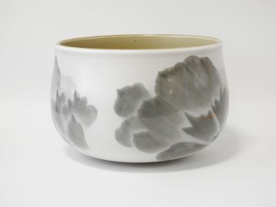 un bol blanc orné de fleurs grises, posé sur une surface blanche