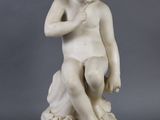 a white marble statue of a boy sitting on a rock