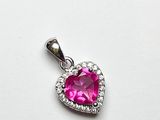 un gros plan d'un pendentif rose en forme de cœur posé sur une surface blanche