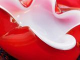 a red heart shaped bowl with a white flower on it