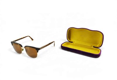 une paire de lunettes de soleil dans un étui, sur fond blanc