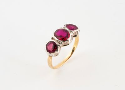 a gold ring with three ruby stones on top