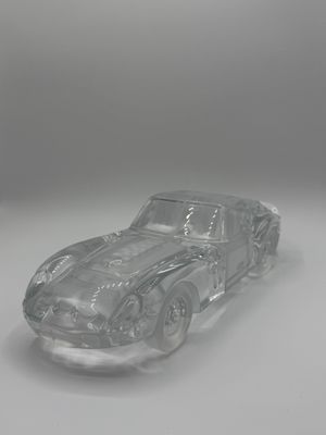 une image représentant une petite voiture en verre transparent posée sur une surface blanche