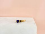 une broche de revers ornée d'une pierre bleue posée sur un bloc blanc