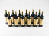 six bottles of wine lined up in a row on a white surface