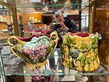a man taking a picture of two vases in a glass case