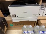 three bottles of water sitting next to a printer on a shelf
