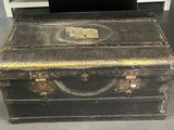une vieille malle posée par terre à côté d'une table